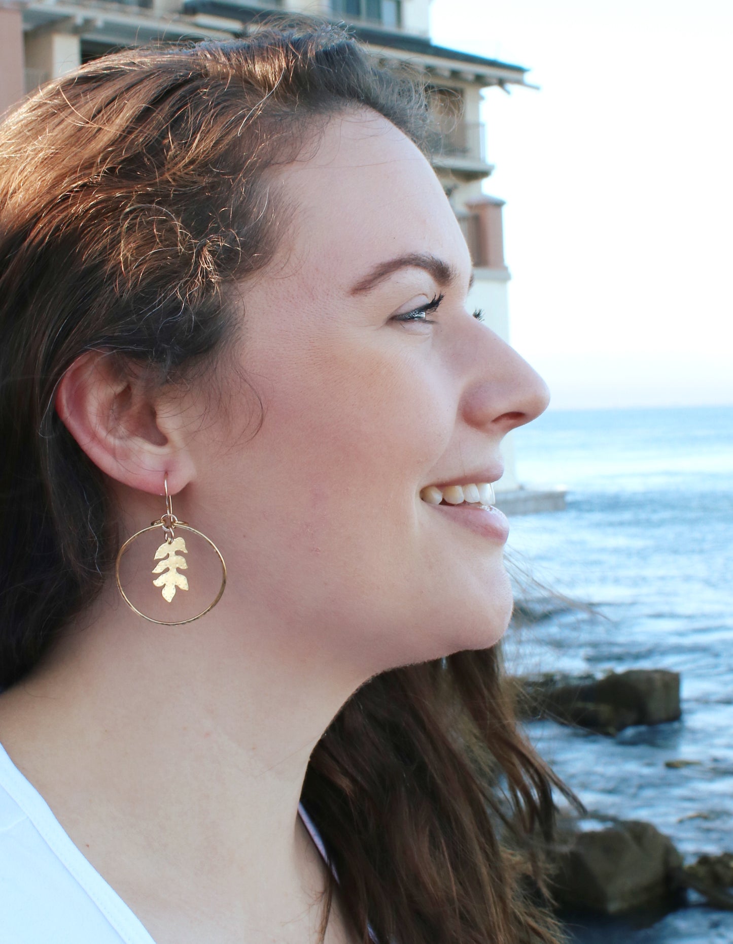 Woman wearing handcrafted brass sassafras hoops, earthy bohemian jewelry inspired by nature and grounded elegance.