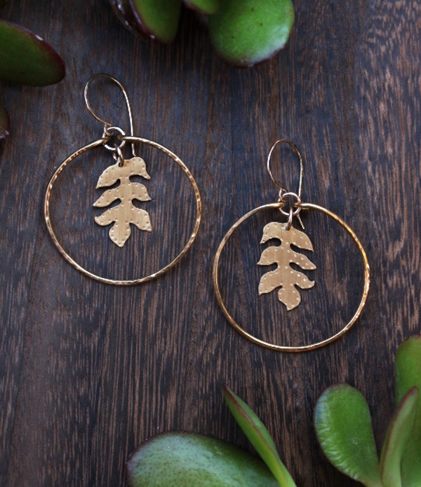 Handcrafted brass sassafras leaf hoops with gold-filled accents, nature-inspired jewelry symbolizing protection and renewal.