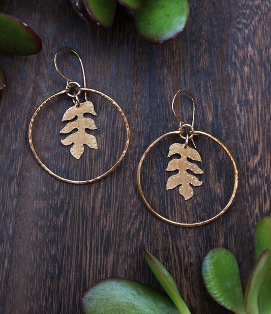 Handcrafted brass sassafras leaf hoops with gold-filled accents, nature-inspired jewelry symbolizing protection and renewal.